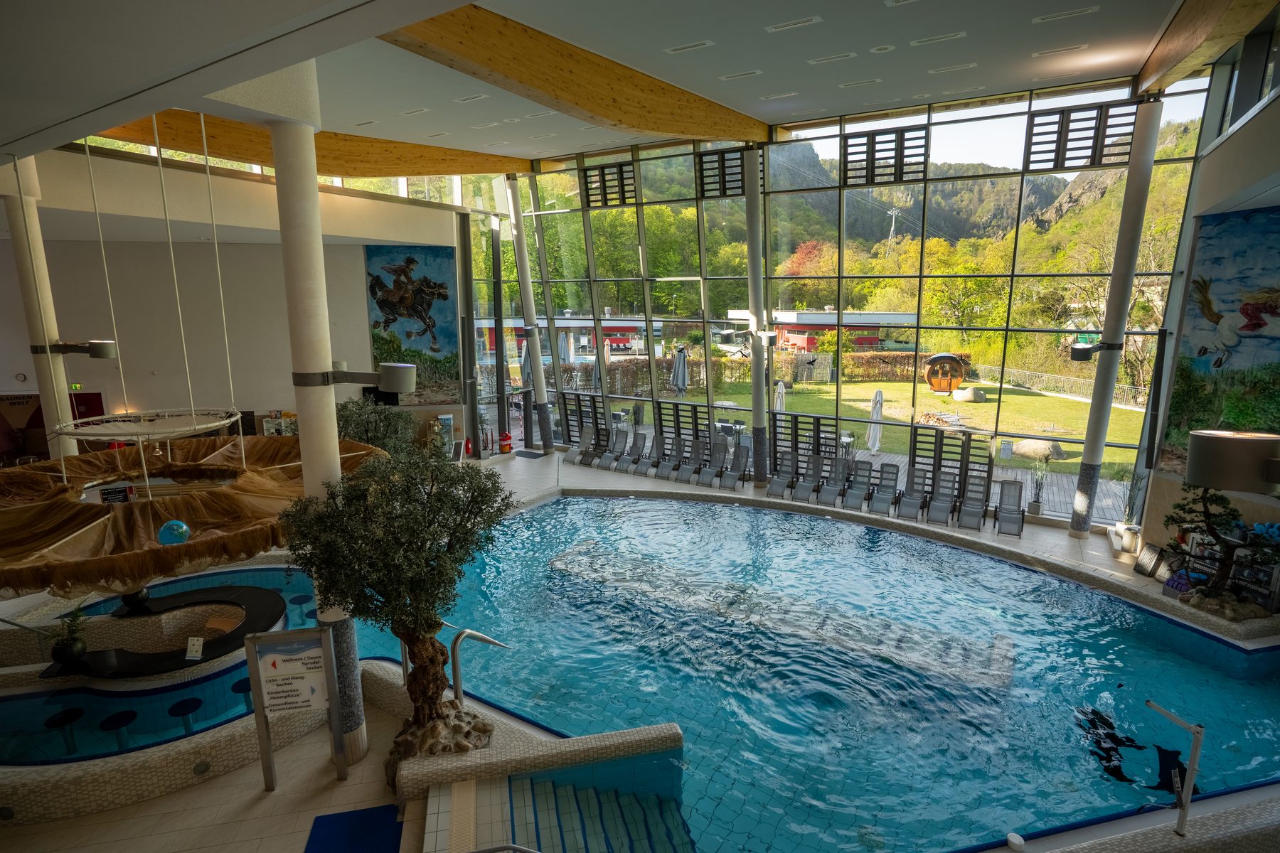 Innenbecken der Bodetal Therme mit gro&szlig;er Fensterfront und Blick ins Bodetal